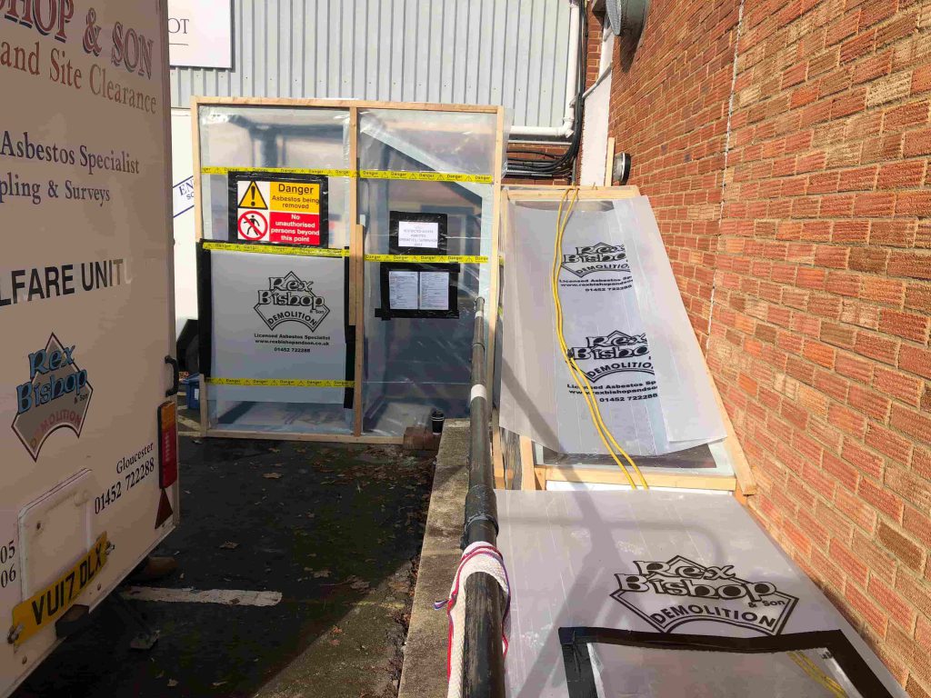 Asbestos removal tent with warning signs outside of the side of a building
