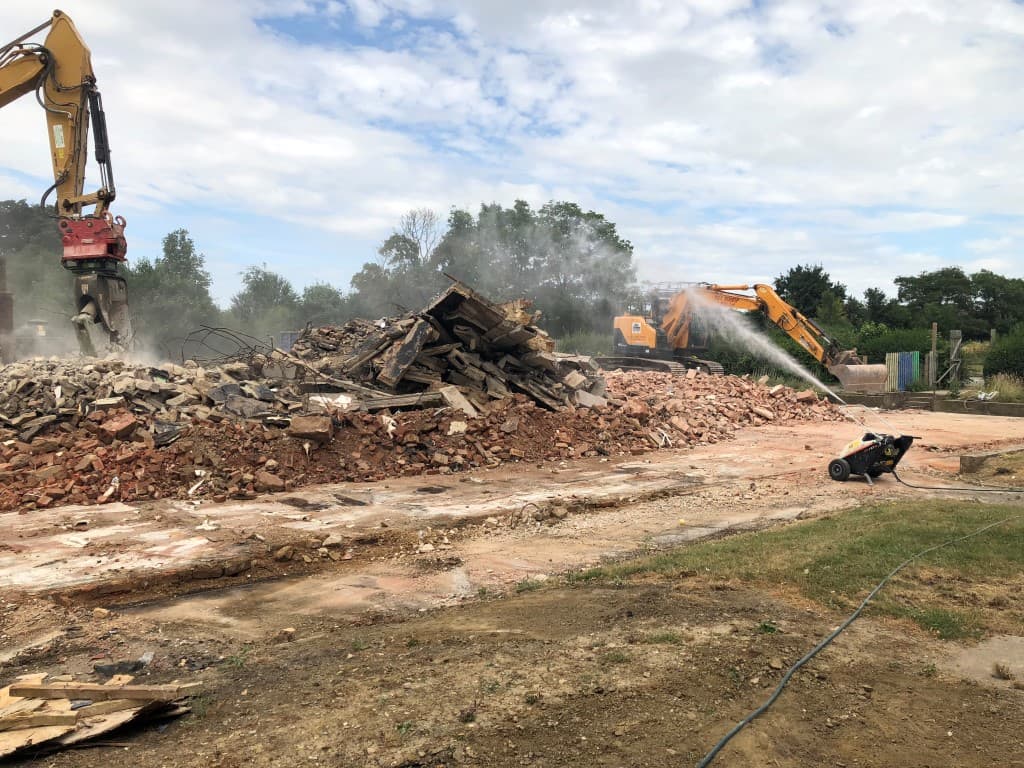 Machine spraying a stream of water over a pile of rubble