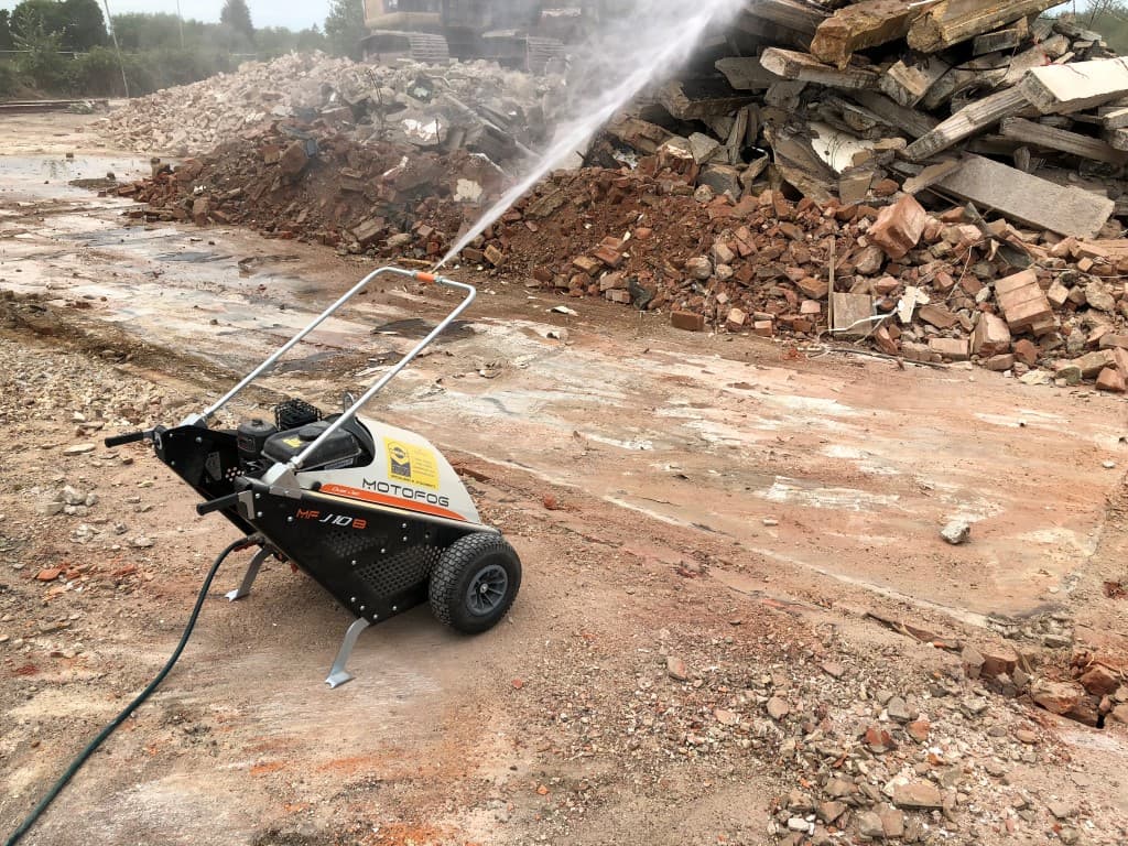 Machine spraying a stream of water over a pile of rubble