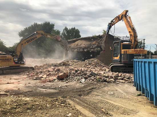 Two diggers grabbing rubble from a pile in the middle