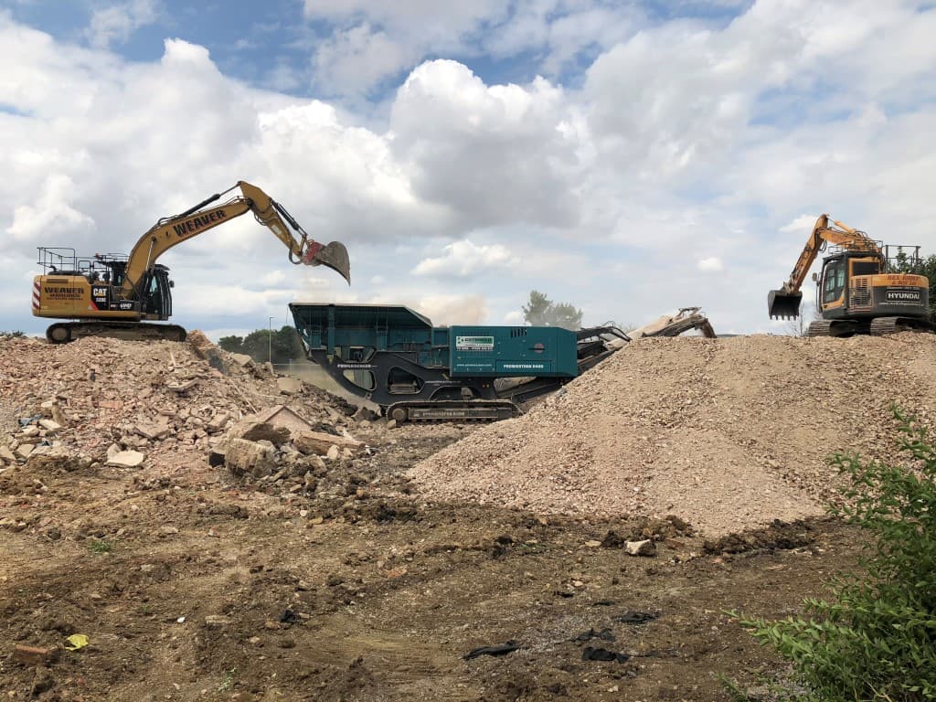 Digger filling up a container with rubble