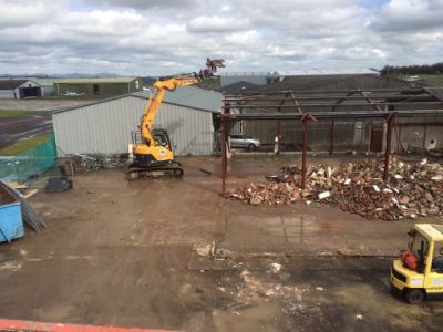 Digger demolishing the roof of a building