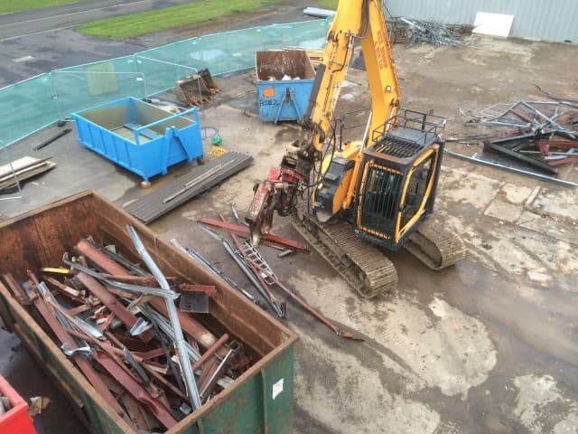 Digger lifting rubble into a container