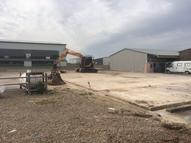 Digger in front of a hangar