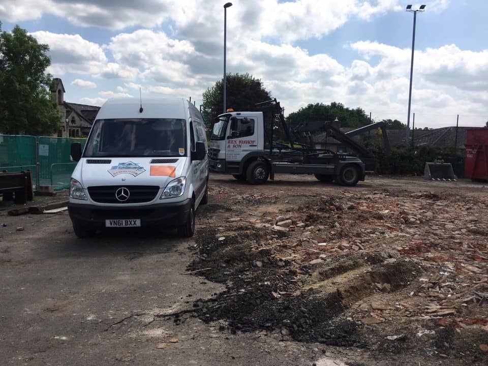 Rex Bishop van outside next to a pile of rubble