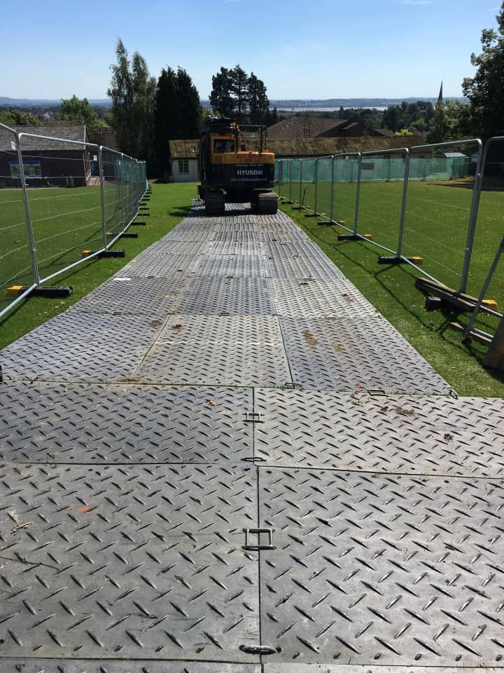 Digger rolling over some metal sheets