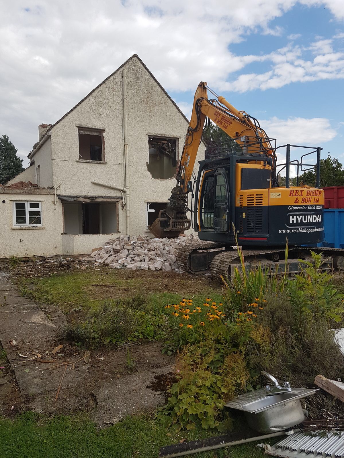 Digger in front of an abandoned house