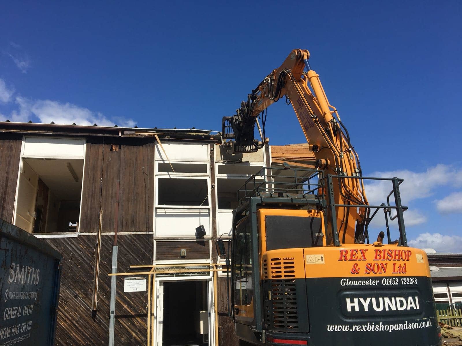 Digger ripping down the roof outside of the moat school building