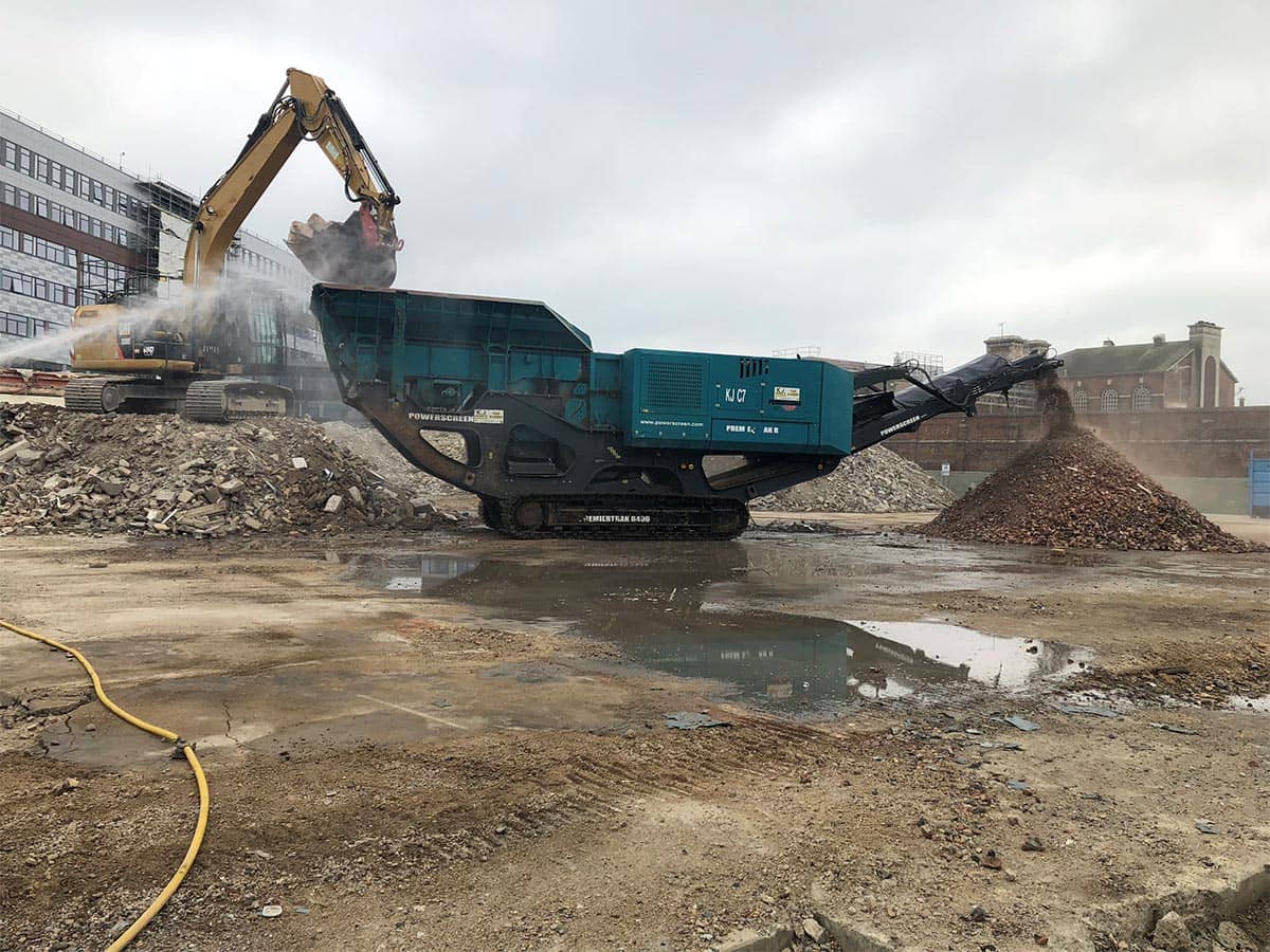 Digger filling up a green container with rubble