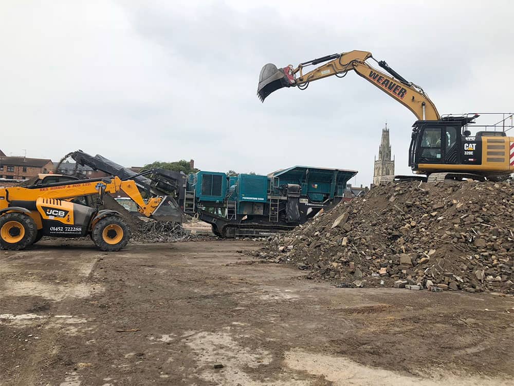 Two diggers behind a pile of rubble